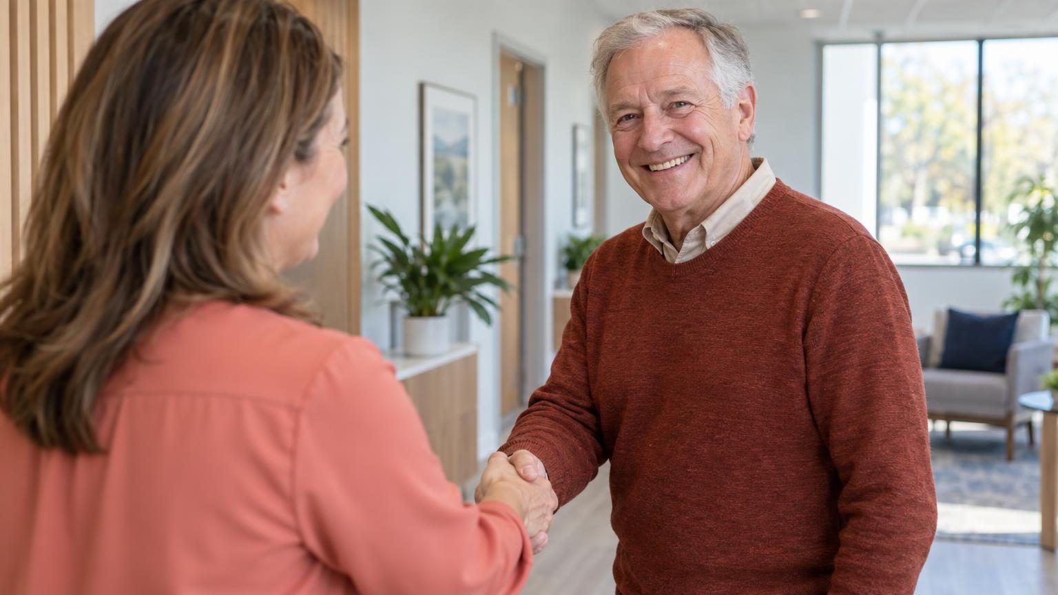 Smiling older man shaking hands with his audiologist at the end of an appointment