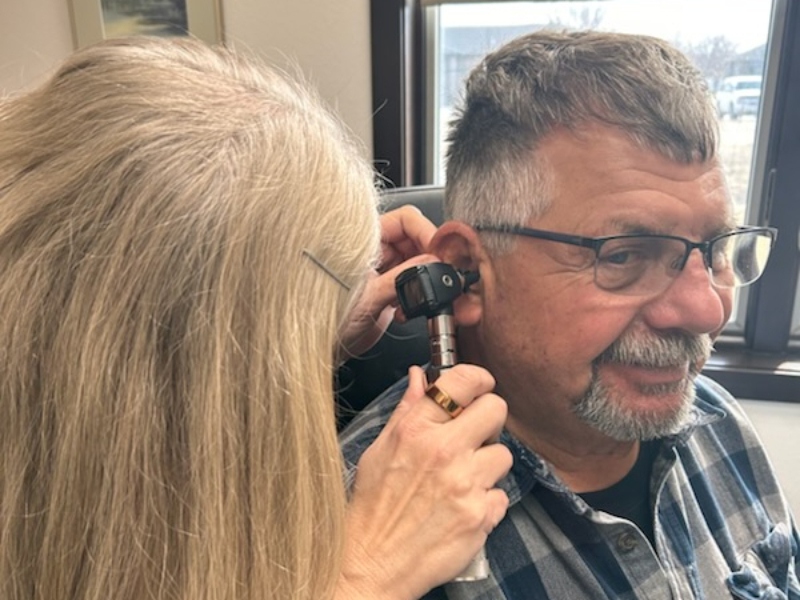 Dr. Fuchs examining a patient's ear with an otoscope during a hearing test at AUDIO-LOGIC, PC in Columbus, NE