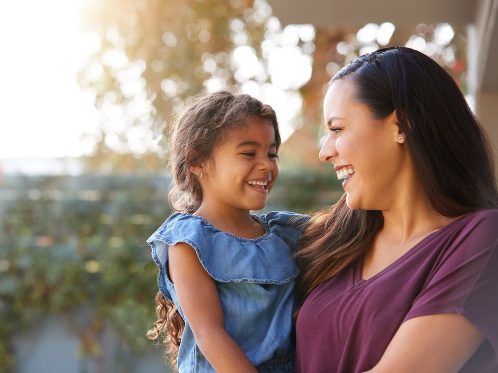 Smiling mother holding her young daughter, a pediatric hearing test patient at AUDIO-LOGIC, PC in Columbus, NE
