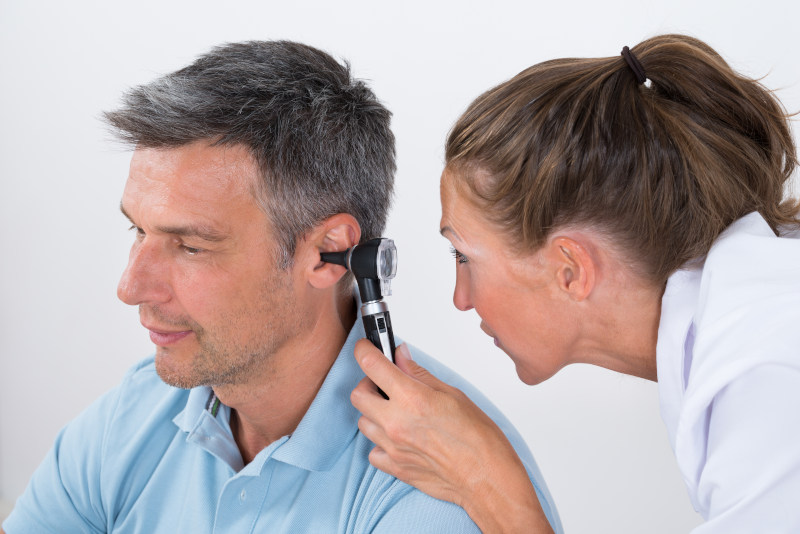 Close-up of a female doctor examining patient's ear with otoscope